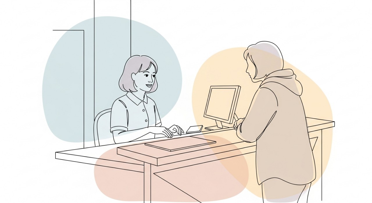 Seorang jururawat sedang melayani pesakit di kaunter pendaftaran klinik kesihatan.