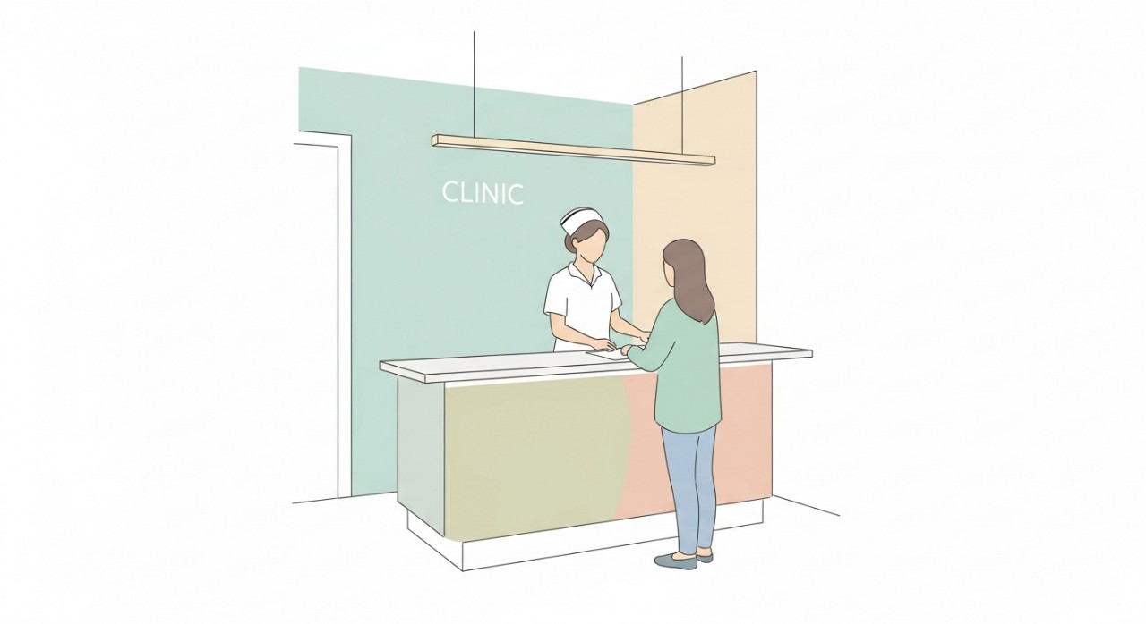 Seorang jururawat sedang berbual dengan seorang pesakit di kaunter pendaftaran klinik.
