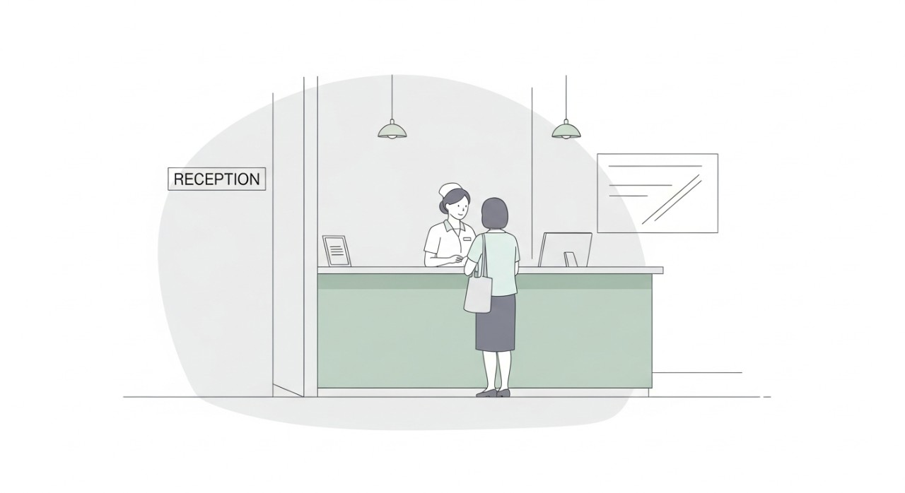 Seorang jururawat sedang melayan pesakit di kaunter pendaftaran untuk urusan janji temu klinik.