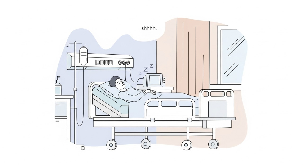 Seorang pesakit sedang berehat di katil wad dengan lampu malap dan tirai ditarik untuk privasi.