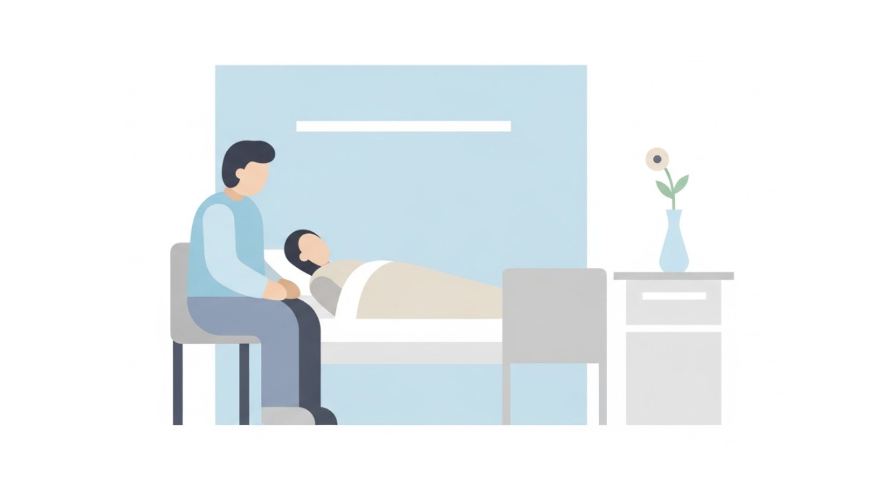 Seorang pelawat sedang duduk di sisi katil sambil berbual dengan pesakit di dalam wad hospital.