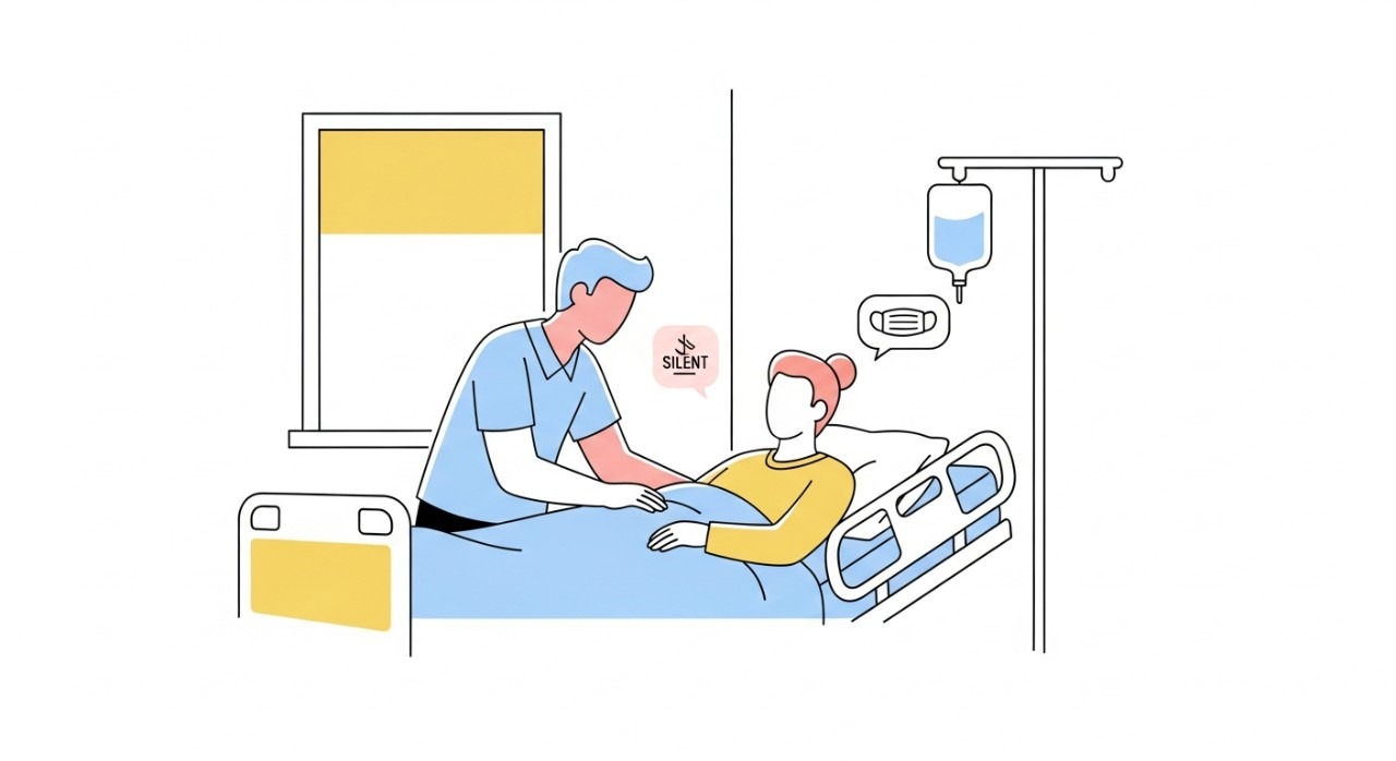 Seorang pelawat sedang berbual dengan lembut bersama pesakit di katil hospital sambil mematuhi etika melawat yang ditetapkan.